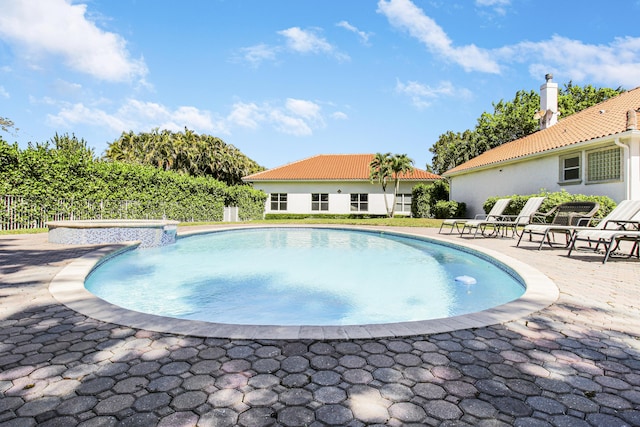 outdoor pool with a patio area and fence