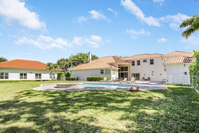 rear view of house featuring a patio, an in ground hot tub, fence, a tiled roof, and a lawn