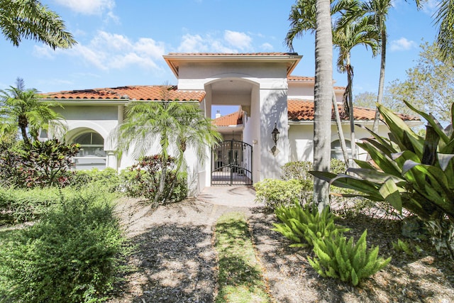 view of front of home with a gate, a tile roof, and stucco siding