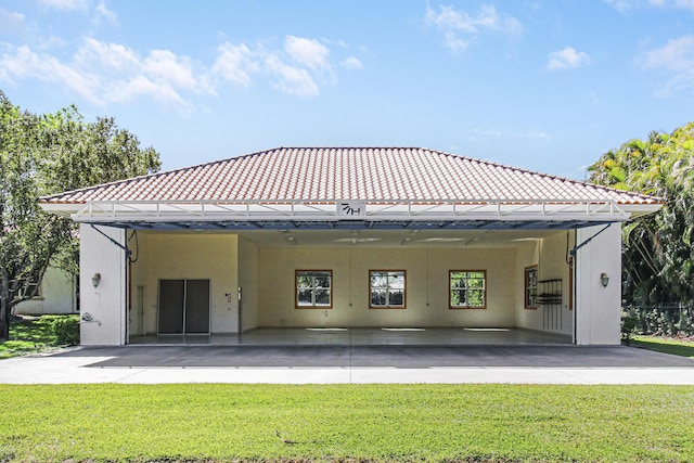 rear view of property featuring a patio area, a yard, a tiled roof, and stucco siding