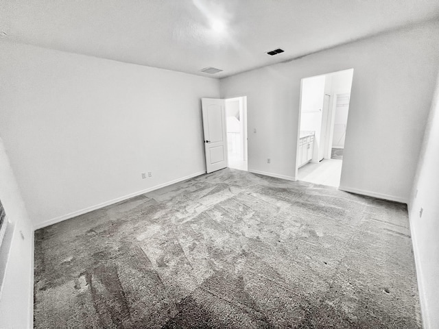 unfurnished bedroom with carpet, connected bathroom, visible vents, and baseboards