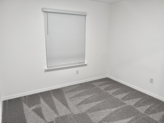 carpeted empty room featuring baseboards