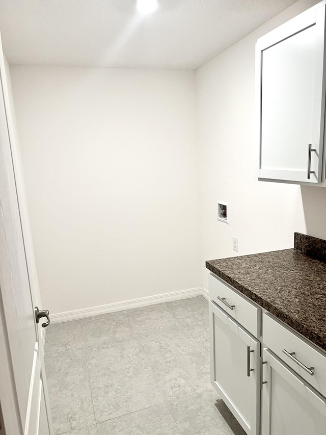 laundry area with hookup for a washing machine, baseboards, and cabinet space