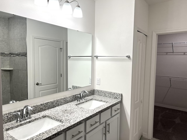 full bathroom featuring a sink, a spacious closet, and double vanity