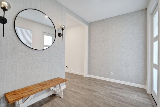 interior space featuring wallpapered walls, baseboards, and wood finished floors