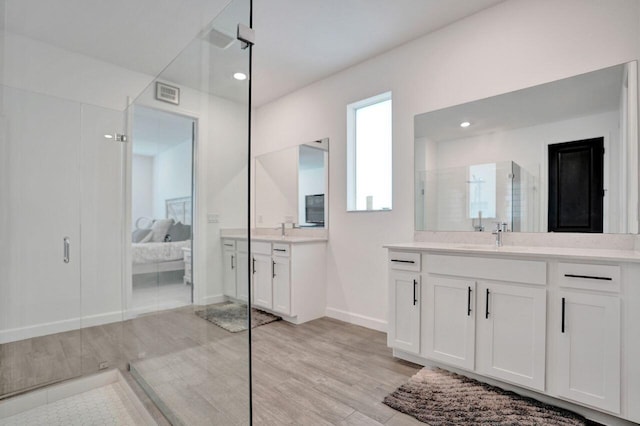 ensuite bathroom with a sink, connected bathroom, two vanities, and walk in shower