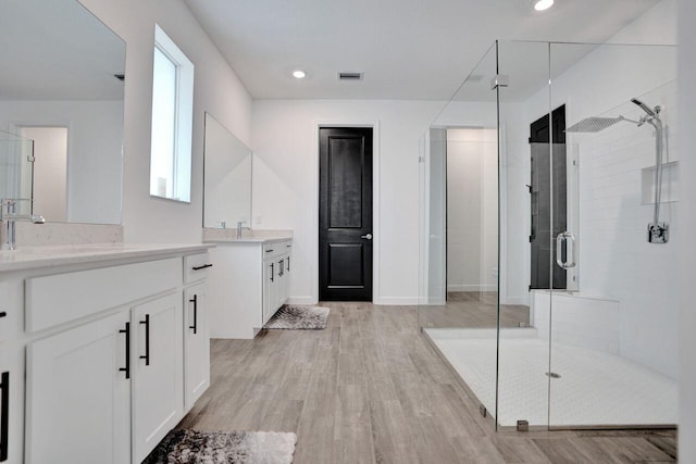 full bathroom with a sink, visible vents, wood finished floors, and a stall shower