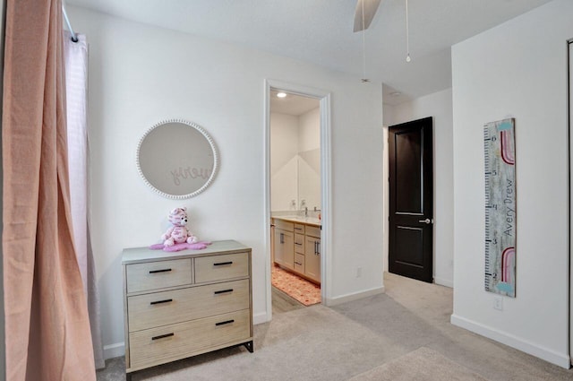 bedroom with baseboards, light carpet, and connected bathroom