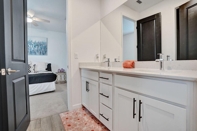 full bath with ensuite bathroom, a sink, wood finished floors, double vanity, and ceiling fan