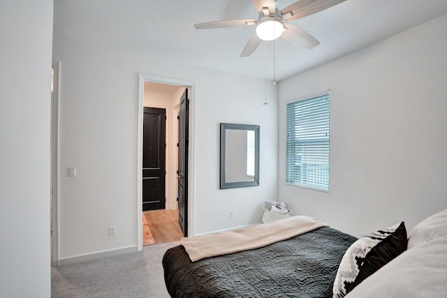 bedroom featuring ceiling fan, ensuite bath, baseboards, and light carpet