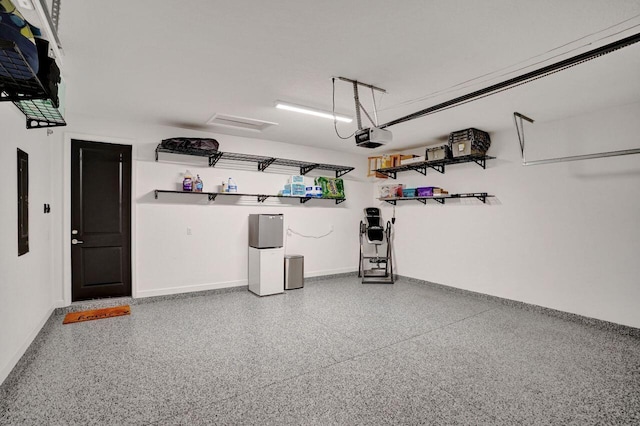 garage featuring baseboards, a garage door opener, and freestanding refrigerator