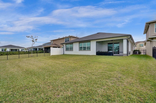 back of house with a fenced backyard, stucco siding, and a yard