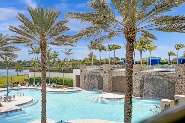 pool with a water view, fence, and a patio area