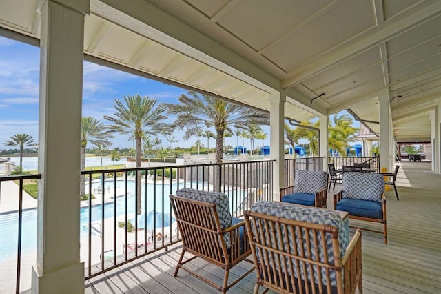 wooden deck featuring a community pool and a water view