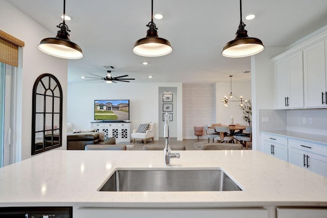 kitchen featuring hanging light fixtures, open floor plan, recessed lighting, and a sink