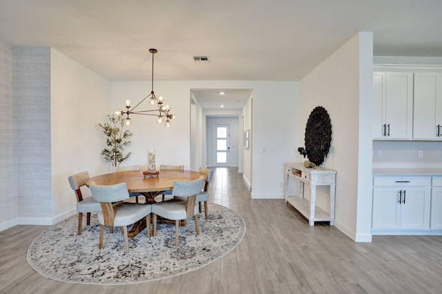 dining area featuring light wood-style flooring, baseboards, visible vents, and a chandelier