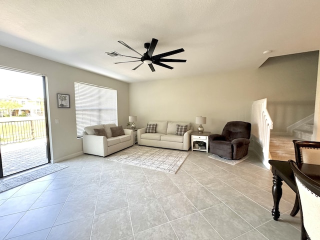 living area with ceiling fan, stairway, light tile patterned flooring, and visible vents