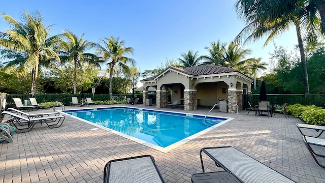 community pool with an outbuilding, fence, and a patio