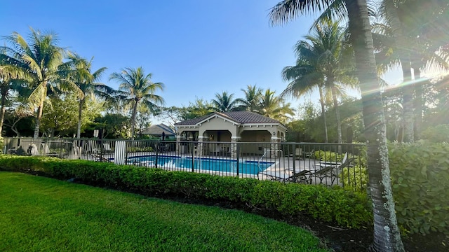 community pool with a patio area, fence, and a yard