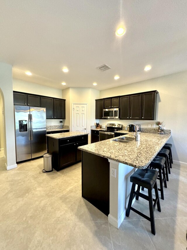 kitchen featuring arched walkways, stainless steel appliances, visible vents, a sink, and a peninsula