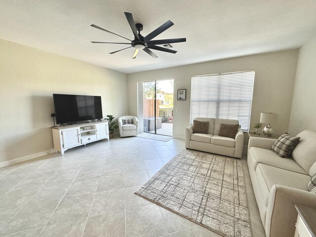 living room featuring a ceiling fan, tile patterned flooring, a textured ceiling, and baseboards