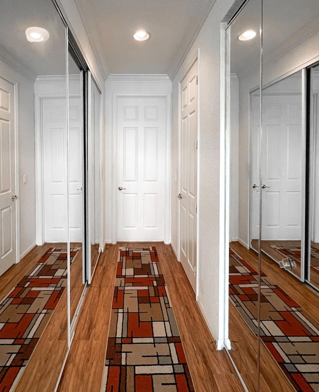 hall with wood finished floors and crown molding