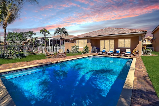 pool at dusk featuring a patio area, fence, and a fenced in pool