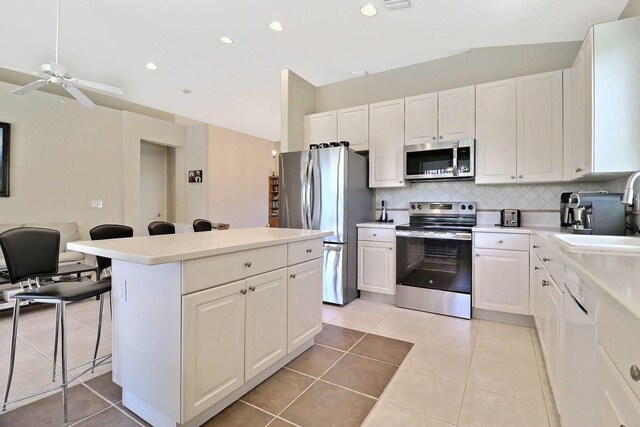 kitchen with backsplash, a center island, a breakfast bar, stainless steel appliances, and a sink