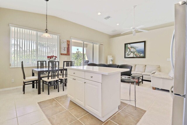 kitchen featuring visible vents, vaulted ceiling, light tile patterned floors, freestanding refrigerator, and white cabinetry