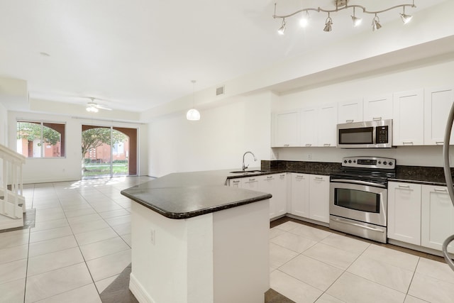 kitchen with dark countertops, visible vents, light tile patterned floors, appliances with stainless steel finishes, and a sink