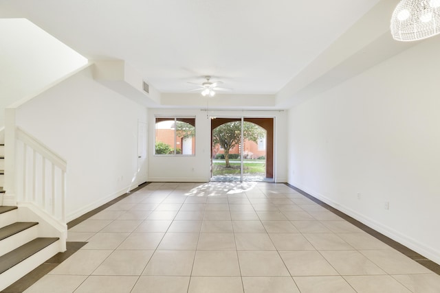 spare room with visible vents, ceiling fan with notable chandelier, stairway, light tile patterned floors, and baseboards