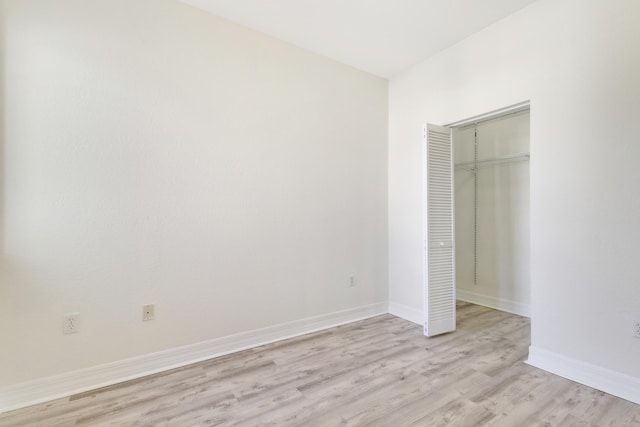 unfurnished bedroom with a closet, baseboards, and light wood-style floors