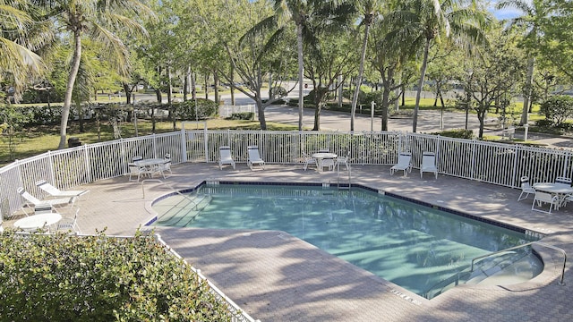 community pool with a patio area and fence