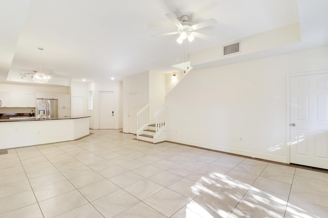 unfurnished living room featuring visible vents, baseboards, stairway, light tile patterned floors, and a ceiling fan