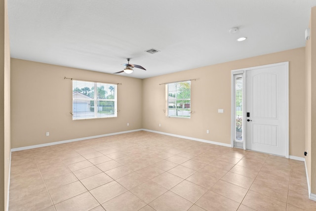 spare room featuring light tile patterned floors, visible vents, baseboards, and ceiling fan