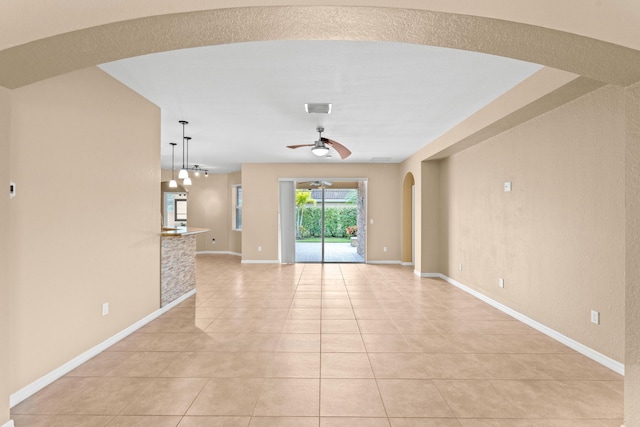 unfurnished living room featuring light tile patterned floors, baseboards, visible vents, arched walkways, and ceiling fan