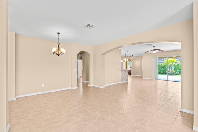 spare room featuring baseboards, ceiling fan with notable chandelier, visible vents, and arched walkways