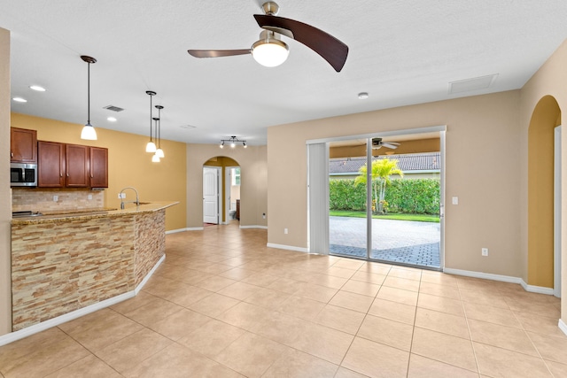 kitchen with stainless steel microwave, visible vents, arched walkways, and backsplash