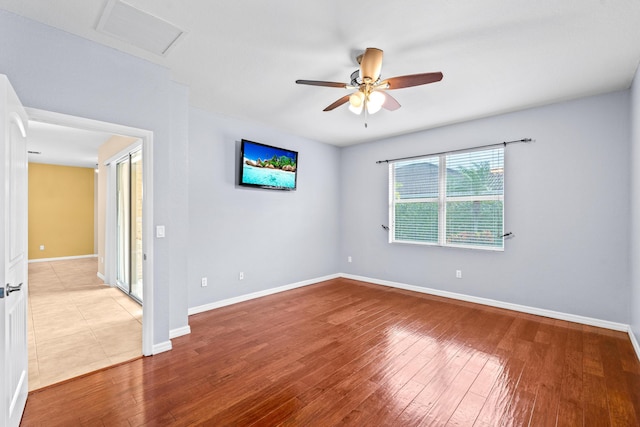 unfurnished room featuring visible vents, attic access, baseboards, and wood finished floors