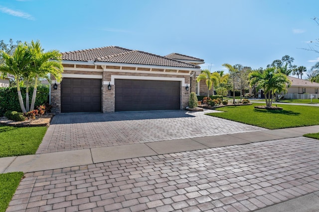 view of front of home with a garage, a tile roof, decorative driveway, and a front yard