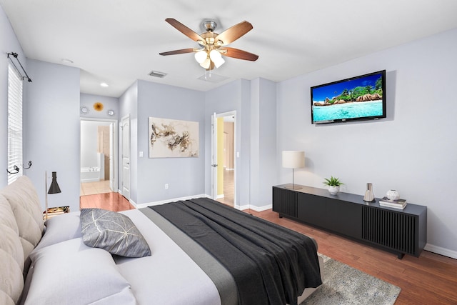 bedroom featuring visible vents, a ceiling fan, wood finished floors, connected bathroom, and baseboards