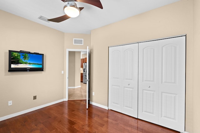 unfurnished bedroom featuring stainless steel refrigerator with ice dispenser, wood finished floors, visible vents, and baseboards