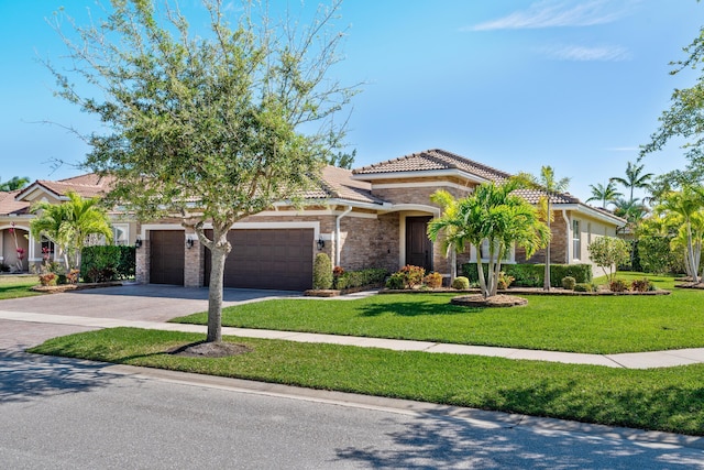 view of front of home with a front lawn, a tiled roof, stone siding, and driveway