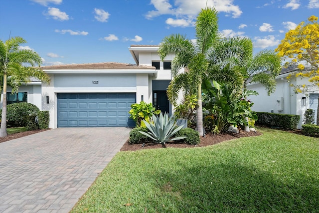 view of front of property with a garage, stucco siding, decorative driveway, and a front yard