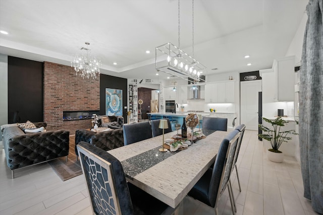 dining space featuring a fireplace, a chandelier, a raised ceiling, and recessed lighting