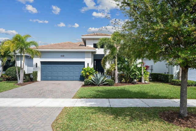 view of front of house with a front yard, decorative driveway, an attached garage, and stucco siding