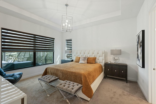 carpeted bedroom featuring a raised ceiling, baseboards, and an inviting chandelier