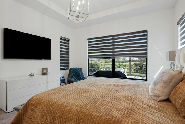 carpeted bedroom with a raised ceiling and an inviting chandelier