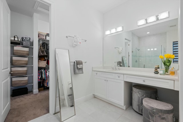 bathroom featuring a walk in closet, a stall shower, vanity, baseboards, and tile patterned floors