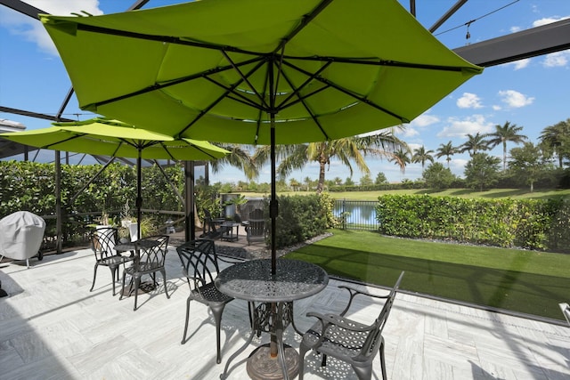 view of patio featuring glass enclosure, fence, and a water view